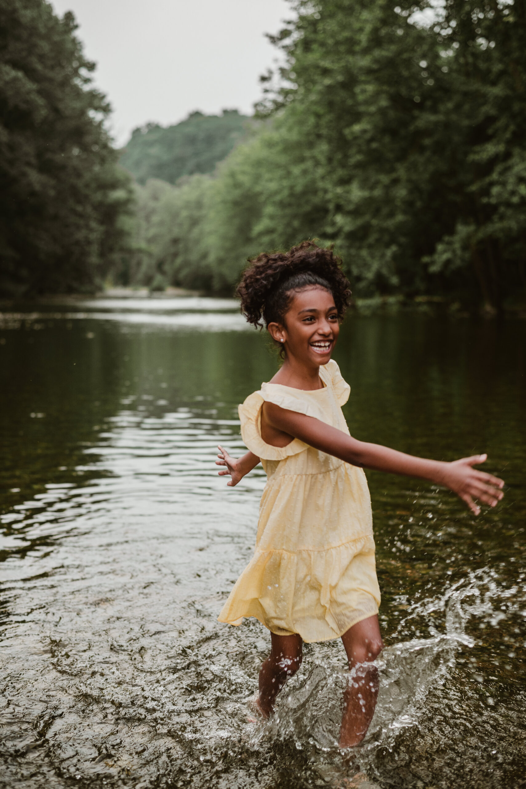 young girl splashing in river for summer mini session