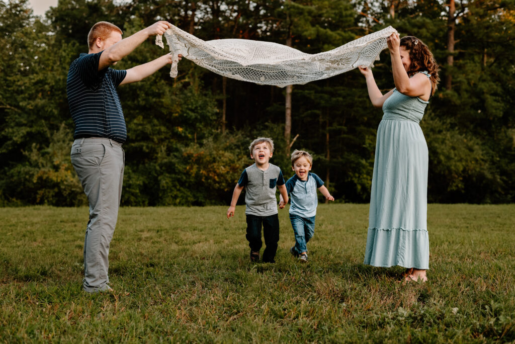 Children running under a blanket held by mom and dad during a playful family photo session in Annapolis, capturing candid joy and connection.
